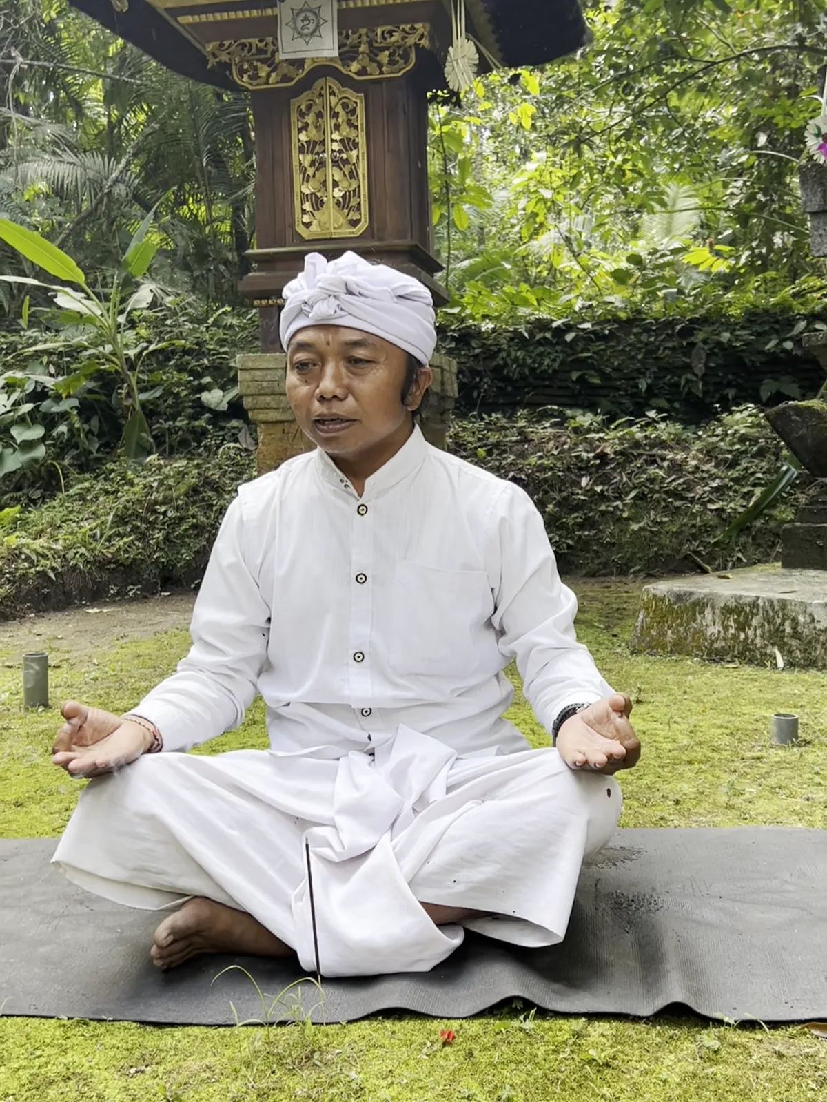 A man meditating, dressed in white, in the Balinese nature