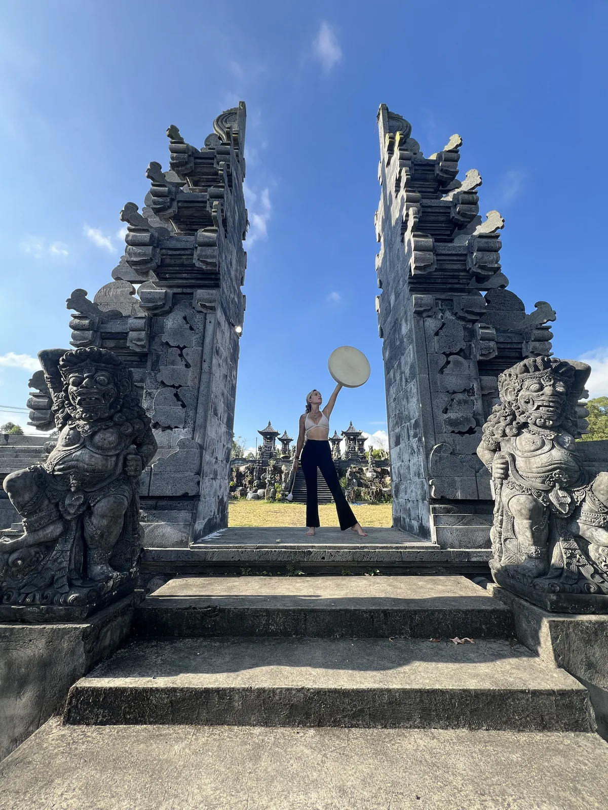 A Balinese split gate framed by guardian statues, under a wide blue sky