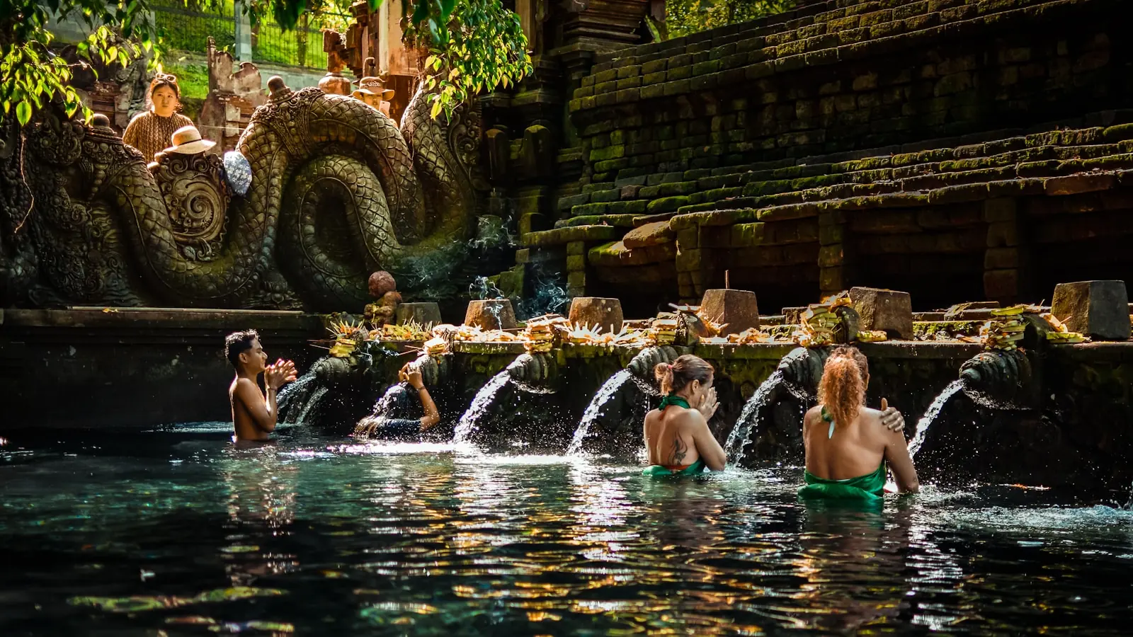 Water purification ceremony in a Balinese temple, a figure in prayer beneath the sacred spring