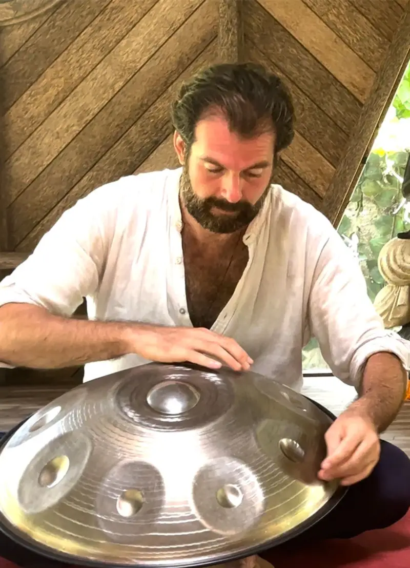 Zhenya Topov, musician, playing the handpan inside a wooden pavilion in Bali