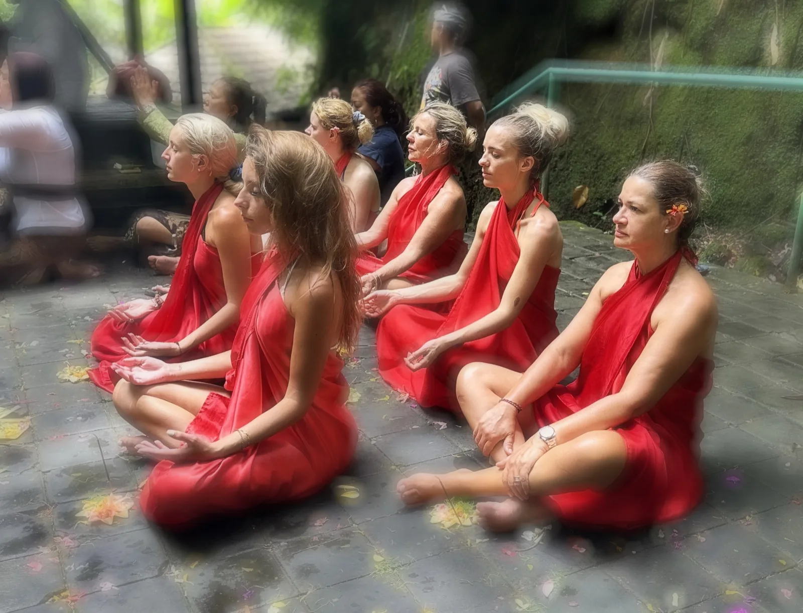 Circle of women in red robes meditating during a Balinese ceremony, group retreat